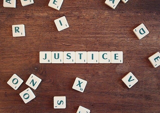 Scrabble tiles spelling the word justice on a wooden table