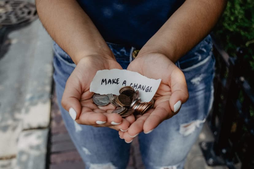 Cupped hands holding coins and a handwritten note reading make a change