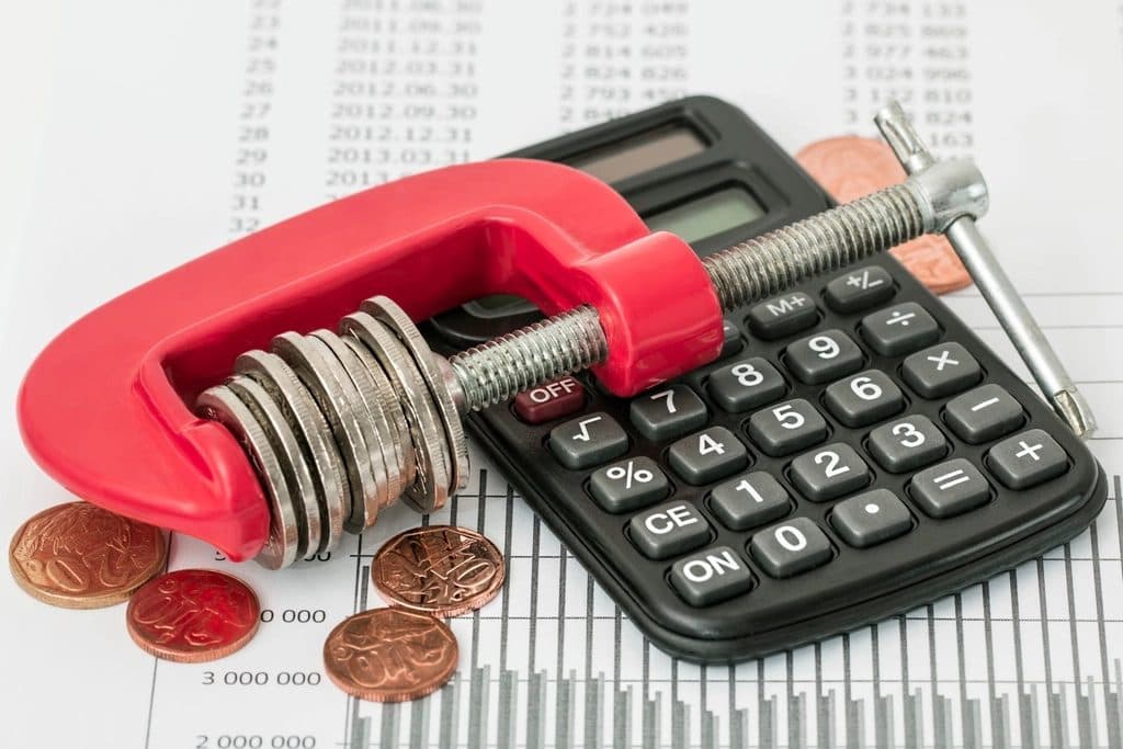 A stack of coins held in a clamp beside a calculator