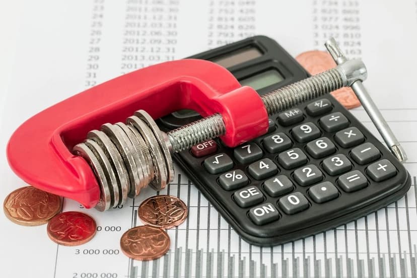 A stack of coins held in a clamp beside a calculator
