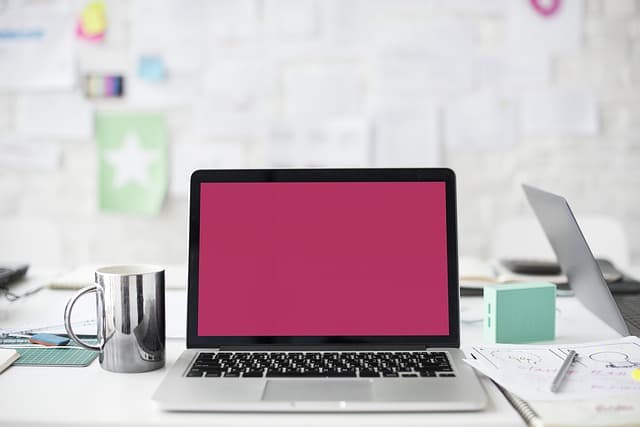 An open laptop on a desk in a bright home office