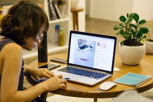 A person working on a laptop at a table by a window