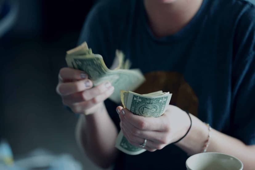 Hands counting a small stack of banknotes