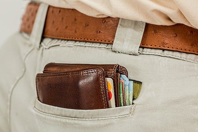 A leather wallet full of cards in the back pocket of a pair of jeans