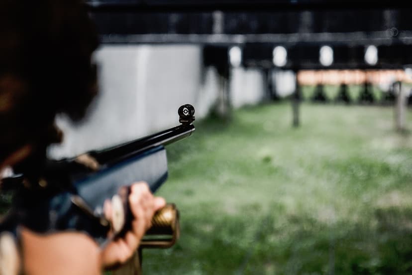 A person aiming a rifle towards targets at an outdoor range
