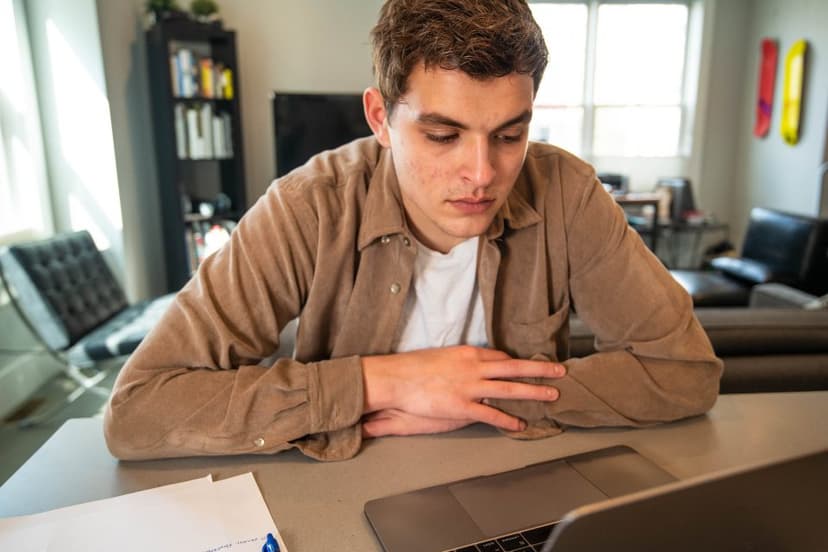 A person sitting at a table looking down at a laptop