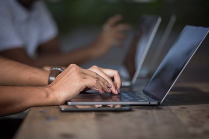 Hands typing on a laptop keyboard at a desk