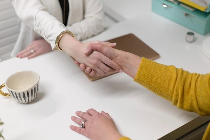 Two people shaking hands across a table
