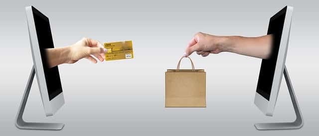 An illustration of hands passing a card and a shopping bag between two monitors