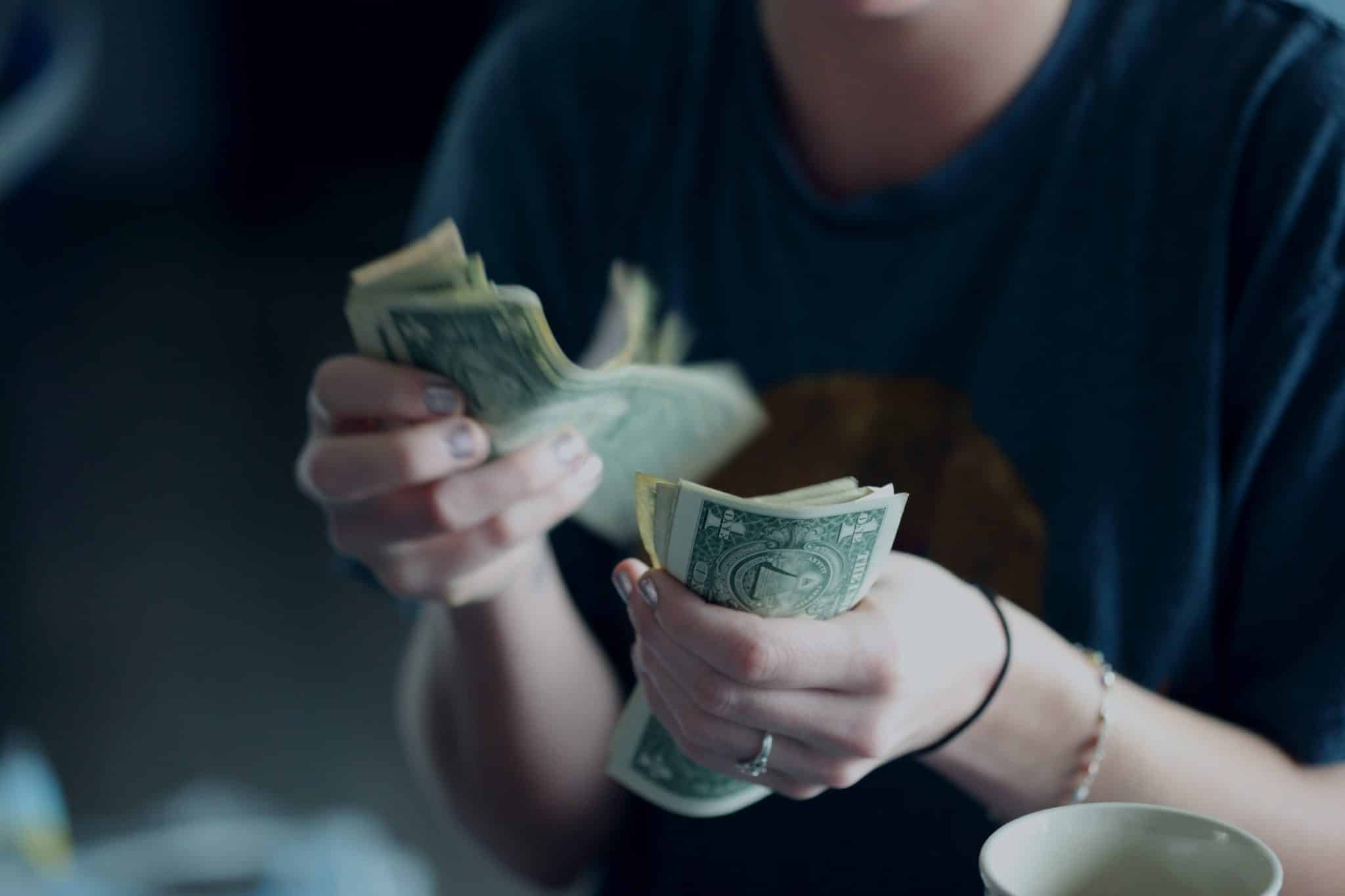 Hands counting a small stack of banknotes