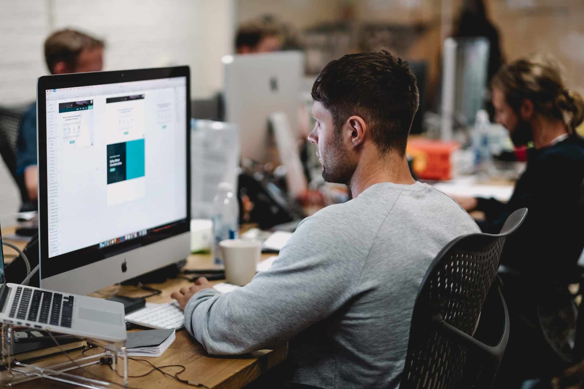 A person working at a desktop computer in an open plan office