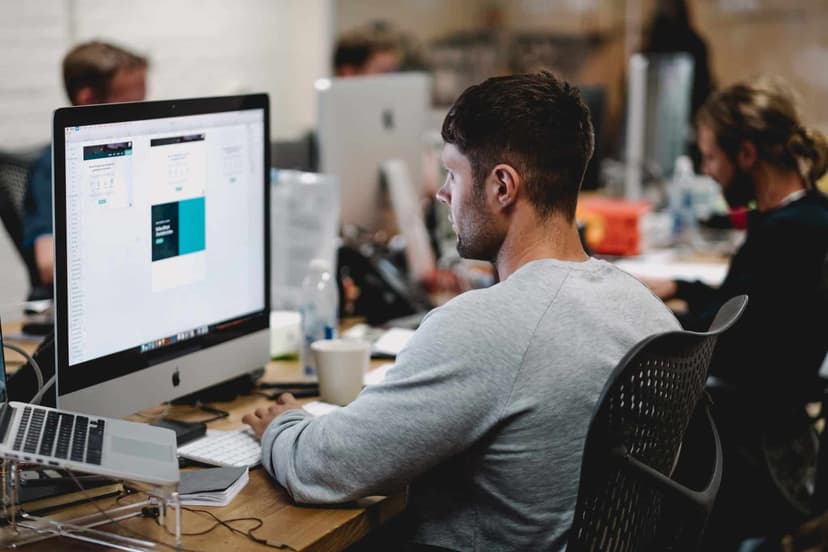 A person working at a desktop computer in an open plan office