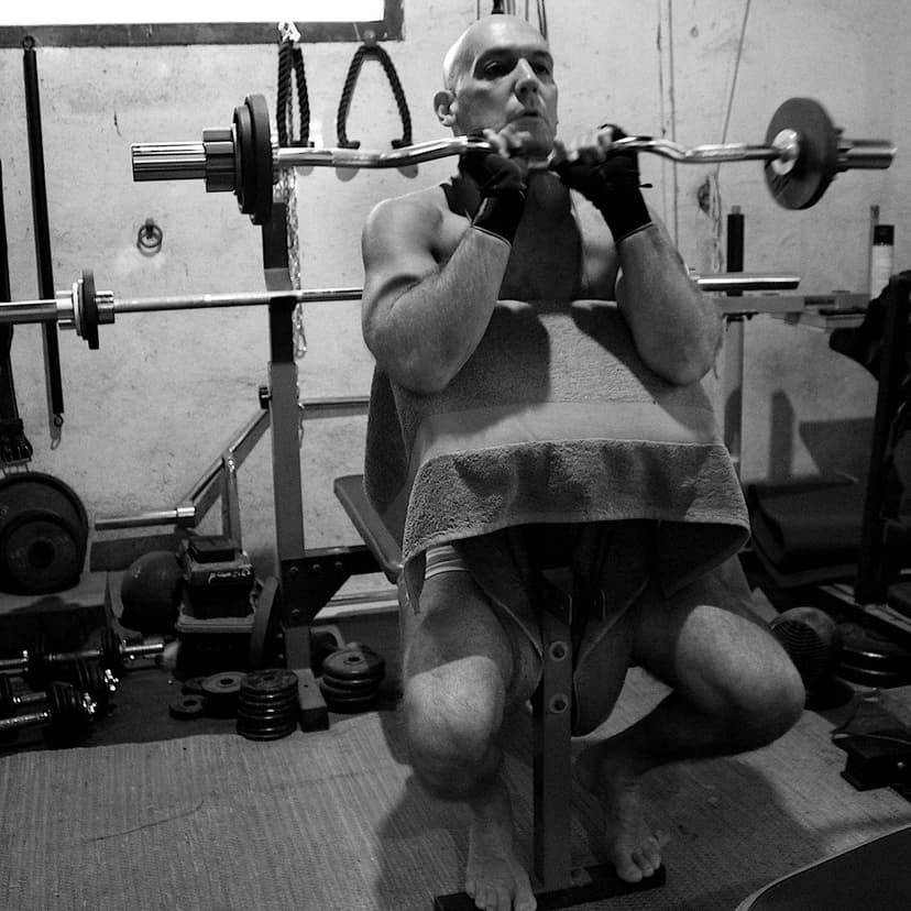 A black and white photograph of a person lifting a barbell in a gym