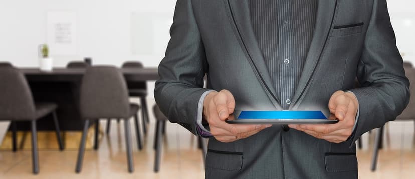 A person in a suit holding a tablet in a meeting room